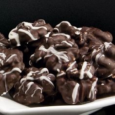 a white plate topped with chocolate covered donuts on top of a table next to a black background