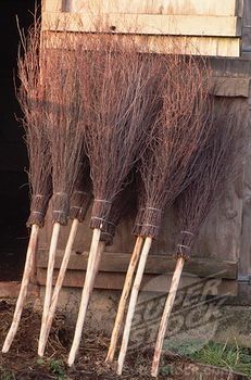 four brooms are lined up in front of a building with wooden poles sticking out of it