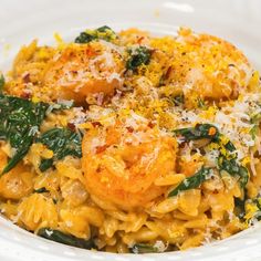 pasta with shrimp, spinach and parmesan cheese in a white bowl on a table