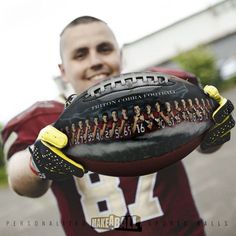 a man holding a football in his hands with the team on it's back