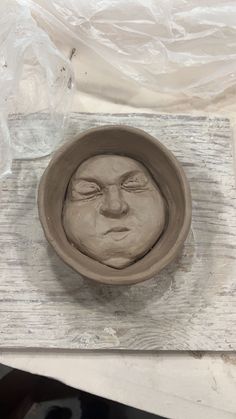 a clay face sitting in a bowl on top of a table