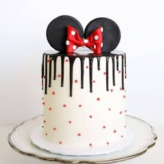 a mickey mouse cake with red polka dots and black ears on top, decorated with chocolate drips