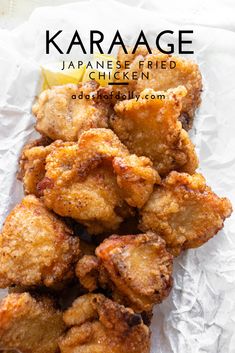 some fried food sitting on top of a piece of wax paper with lemon wedges