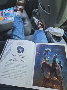 an open book sitting on top of a car seat next to someone's feet