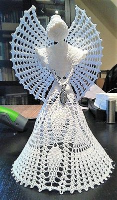 a white crocheted angel sculpture sitting on top of a table next to a computer mouse