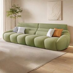 a green couch sitting on top of a hard wood floor next to a white rug