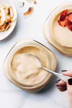 two jars filled with food sitting on top of a white counter next to plates and utensils