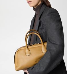 Characterized by maxi zip pulls, straps that elegantly cover the zip when closed, Tod's Darsena is defined by essential and feminine lines. Featuring characteristic tubular handles, it comes with the Tod's logo stamped on the front and a wrapped side padlock, a sophisticated distinctive trait. Here in fine natural-grained calfskin leather, this is a model with a distinctly urban nature, named after the city of Milan. Formal Calf Leather Bag With Zipper Closure, High-end Formal Bag With Zipper Closure, Elegant Calf Leather Bag With Zipper Closure, Hermes Bag With Engraved Zipper Pull For Everyday Use, Elegant Calf Leather Shoulder Bag With Zipper Closure, Urban Nature, Area Codes, Gift Boutique, Logo Stamp