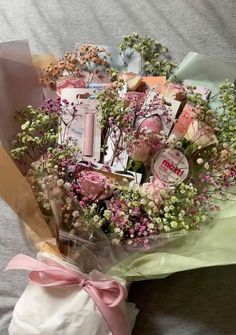 a bouquet of flowers sitting on top of a bed next to a bag filled with items