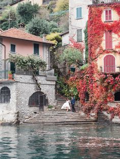 a bride and groom walking down some steps by the water