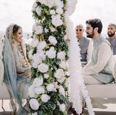 a man and woman sitting on a couch next to each other in front of flowers