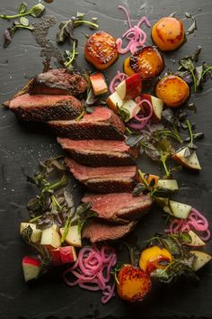 sliced steak and vegetables on a slate board