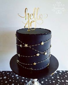 a black cake with gold stars on top and the word hello are spelled in cursive writing