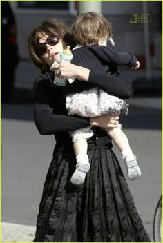 a woman holding a baby in her arms while walking down the street with another child