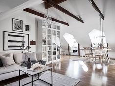 a living room filled with furniture next to a wooden floor covered in white walls and windows