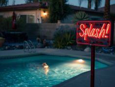 a red neon sign that says sushi in front of a swimming pool at night