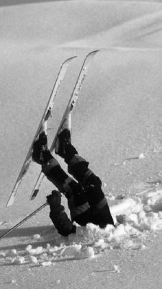 two skiers are upside down in the snow with their skis attached to them