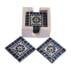 three pieces of blue and white tile with geometric designs on the bottom, one is in an open box