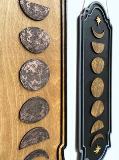 three different types of moon phases hanging on a wall next to a wooden plaque with gold and black designs