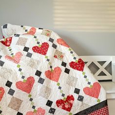 a white bed with a red and black heart quilt on it