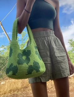 a woman holding a green crocheted purse