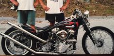 two men standing next to a parked motorcycle