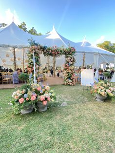 an outdoor event with white tents and flower arrangements