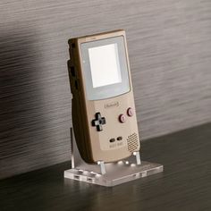 an old nintendo gameboy sitting on top of a wooden table next to a wall