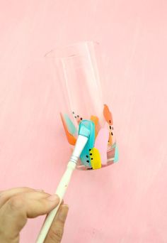 a person holding a toothbrush in front of a cup with some decorations on it