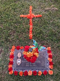 a grave with flowers and a cross in the grass