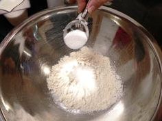 a person is mixing something in a large metal bowl with a spoon on top of it