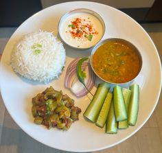 a white plate topped with rice and veggies next to other foods on a table