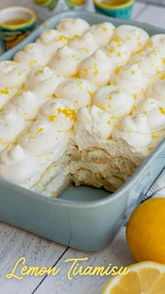 a pan filled with lemon meringue dessert next to sliced oranges and cups