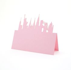 a pink card with a city skyline cut out of it's sides on a white background