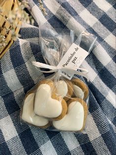 some heart shaped cookies wrapped in plastic on a checkered table cloth with a basket behind them