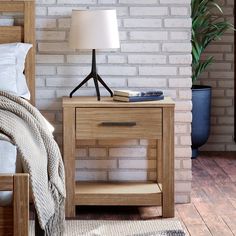 a nightstand with a lamp on it next to a bed