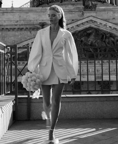 a woman is walking down the street wearing a white jacket and shorts with pom - poms