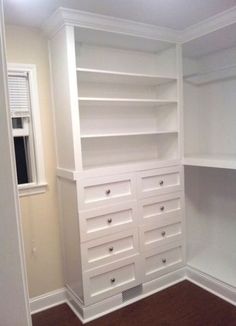 an empty closet with white shelves and drawers on the wall, along with hardwood flooring