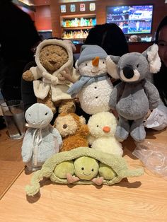 a group of stuffed animals sitting next to each other on a wooden table at a restaurant