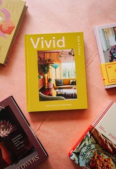 several books are laying on the floor next to each other in front of a pink background