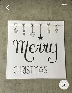 a christmas card with the words merry christmas hanging from a clothes line and ornaments on it