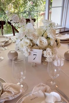 the table is set with white flowers and place cards