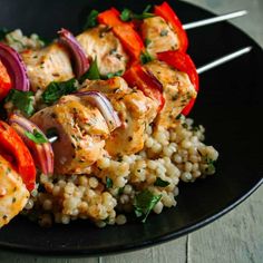 chicken and rice kabobs on a black plate with red onion garnish