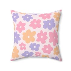 a pink and purple pillow with colorful flowers on it's front, against a white background