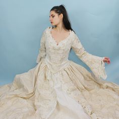 Absolutely INSANE Princess Wedding Dress! Dramatic Ballgown with Bustier Style corset lace up top, long bell sleeves, full skirt, pearl and sequin floral applique, gold shimmery embroidered details, long train, and scalloped lace cutouts. Unbelievable Fairy queen medieval renaissance style look. Size 12, somewhat adjustable with corset. Comes with Matching Rosette GarterBust: 40"-41"Waist: 29"-33"Hips: 82"Length: 56.5"Train: Extra 44" Embroidered Ball Gown For Debutante Ball, Cream Lace Ball Gown, Debutante Ball Gown With Lace Trim And Fitted Bodice, Fitted Embroidered Gown For Debutante Ball, Ball Gown With Lace Sleeves And Fitted Bodice, Lace Ball Gown With Intricate Embroidery, White Rococo Wedding Dress, Rococo Style Ball Gown Wedding Dress, Wedding Ball Gown With Lace Sleeves And Fitted Bodice