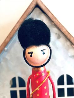 a wooden doll with a red outfit and black hair standing in front of a house