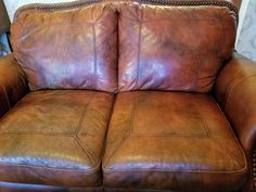 two brown leather couches sitting next to each other