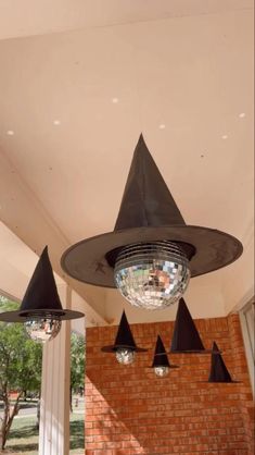 three black cone lights hanging from the ceiling in front of a brick wall and white pillars