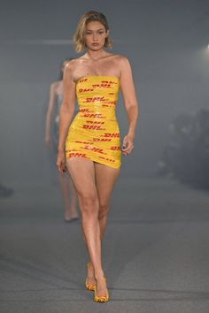 a model walks down the runway in a yellow dress