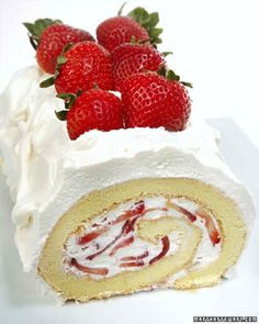 there is a roll with strawberries on top and white frosting next to it